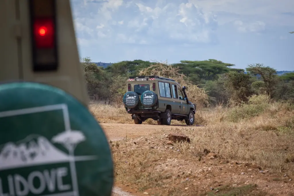 A jeep on a dirt road next to a "Wildo" sign, representing Kilidove Tours 5 days safari Tanzania.