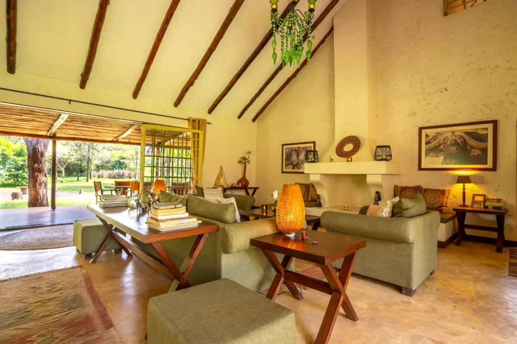 Indoor living room with sofas, wooden furniture, warm lamp, and garden access at Kili Villa
