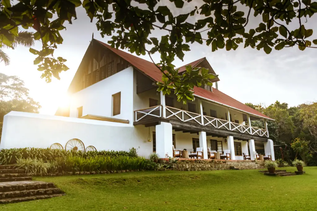 Main House with balcony at sunset, surrounded by green garden at NgareSero Mountain Lodge