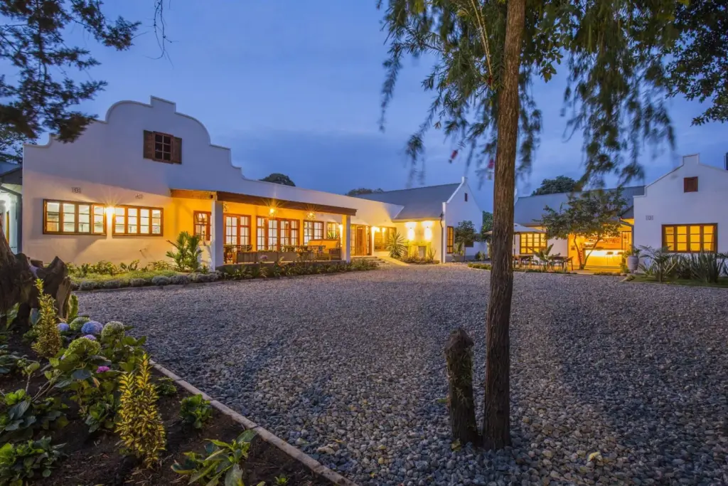 Main entrance at Villa Maua Arusha: twilight view, white building, warm lights, gravel courtyard