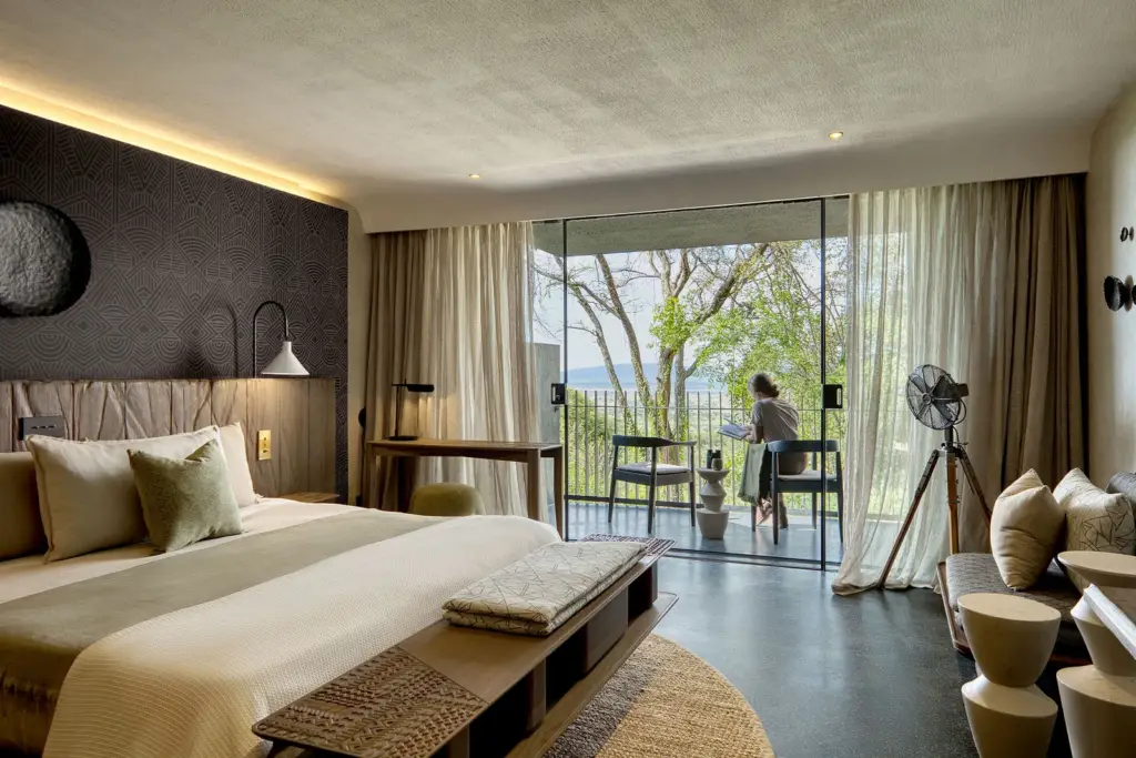 Modern hotel room with balcony views of nature at Serengeti Explorer Elewana.