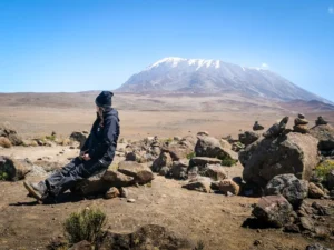 Trekker resting on a rocky ridge above the clouds