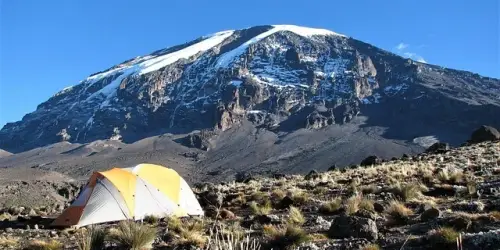 A tent pitched with the majestic Mount Kilimanjaro in the background, ideal for climbers and adventurers.