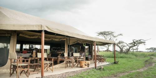 Outside view of Mawe Tented Camp Hotel with dining tables set up in a grassy field