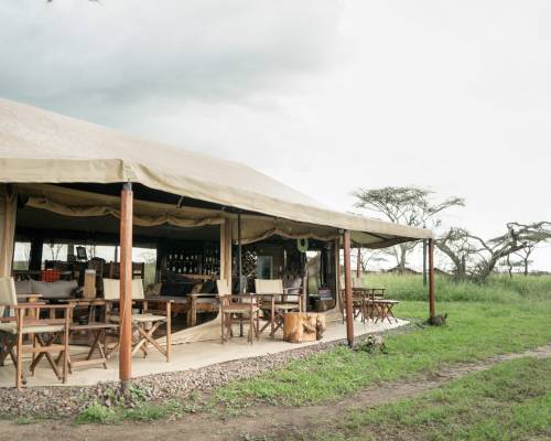 Outside view of Mawe Tented Camp Hotel with dining tables set up in a grassy field