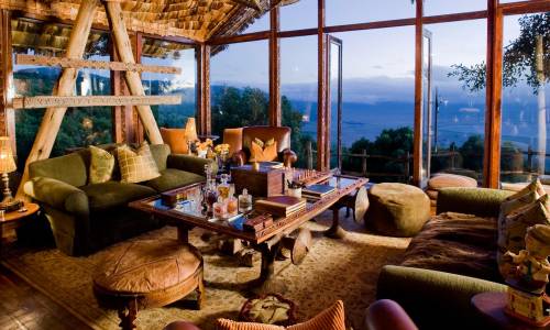 Cozy, inviting living room with large windows overlooking nature, featuring plush sofas, wooden furniture, and warm lighting
