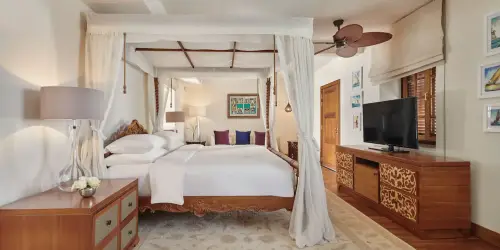 White double bed with TV, curtains, and modern decor at Park Hyatt Zanzibar room