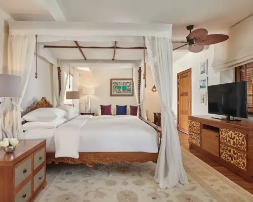 White double bed with TV, curtains, and modern decor at Park Hyatt Zanzibar room