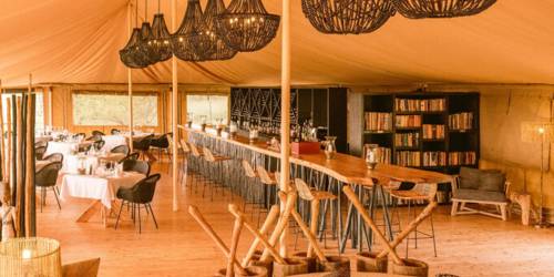 Interior of a cozy tent with elegant lighting, cushioned seating, and a wooden floor