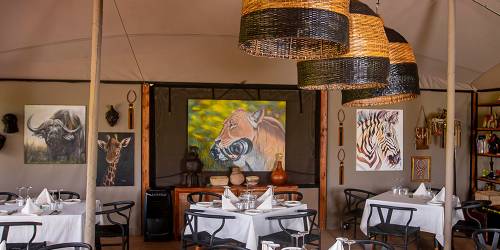 Elegant safari-themed dining area with large wicker pendant lights and wildlife artwork