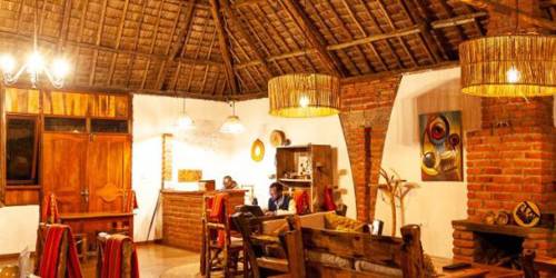 Rustic interior with thatched roof, wood furniture, and warm lighting
