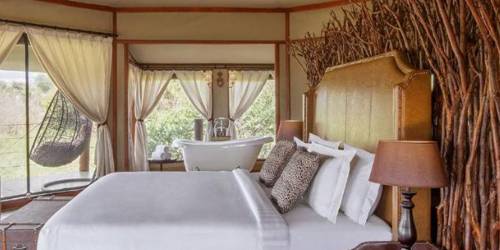 Luxurious tented bedroom with a large bed, chandelier, and elegant rustic decor