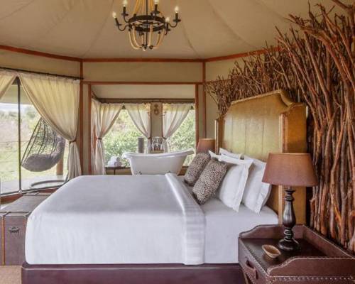 Luxurious tented bedroom with a large bed, chandelier, and elegant rustic decor
