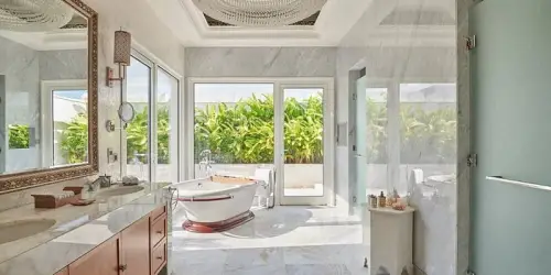 Luxurious bathroom with marble floors, freestanding tub, and greenery at Park Hyatt Zanzibar