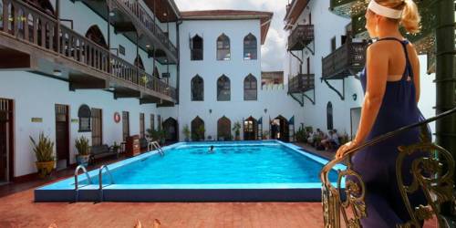 People relaxing by a pool in a courtyard with traditional architecture
